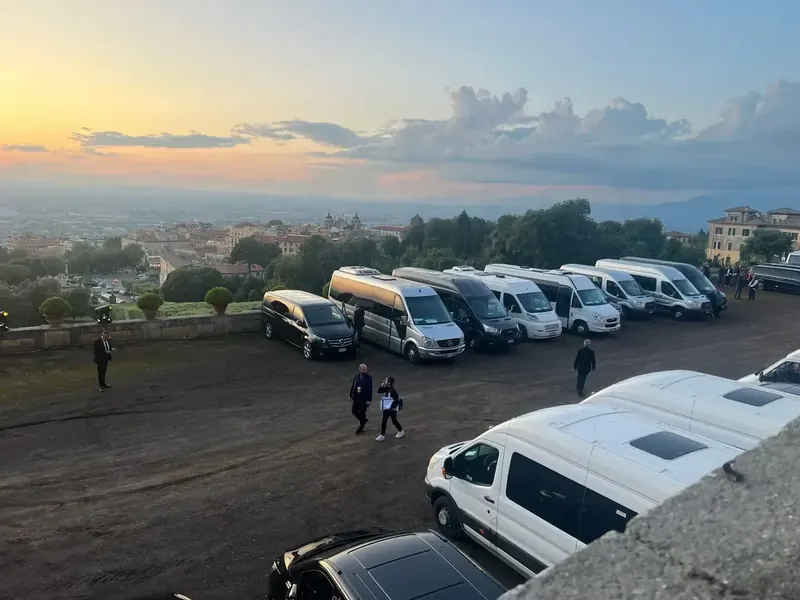 Minibus e van in sosta in un piazzale con vista sulla città al tramonto